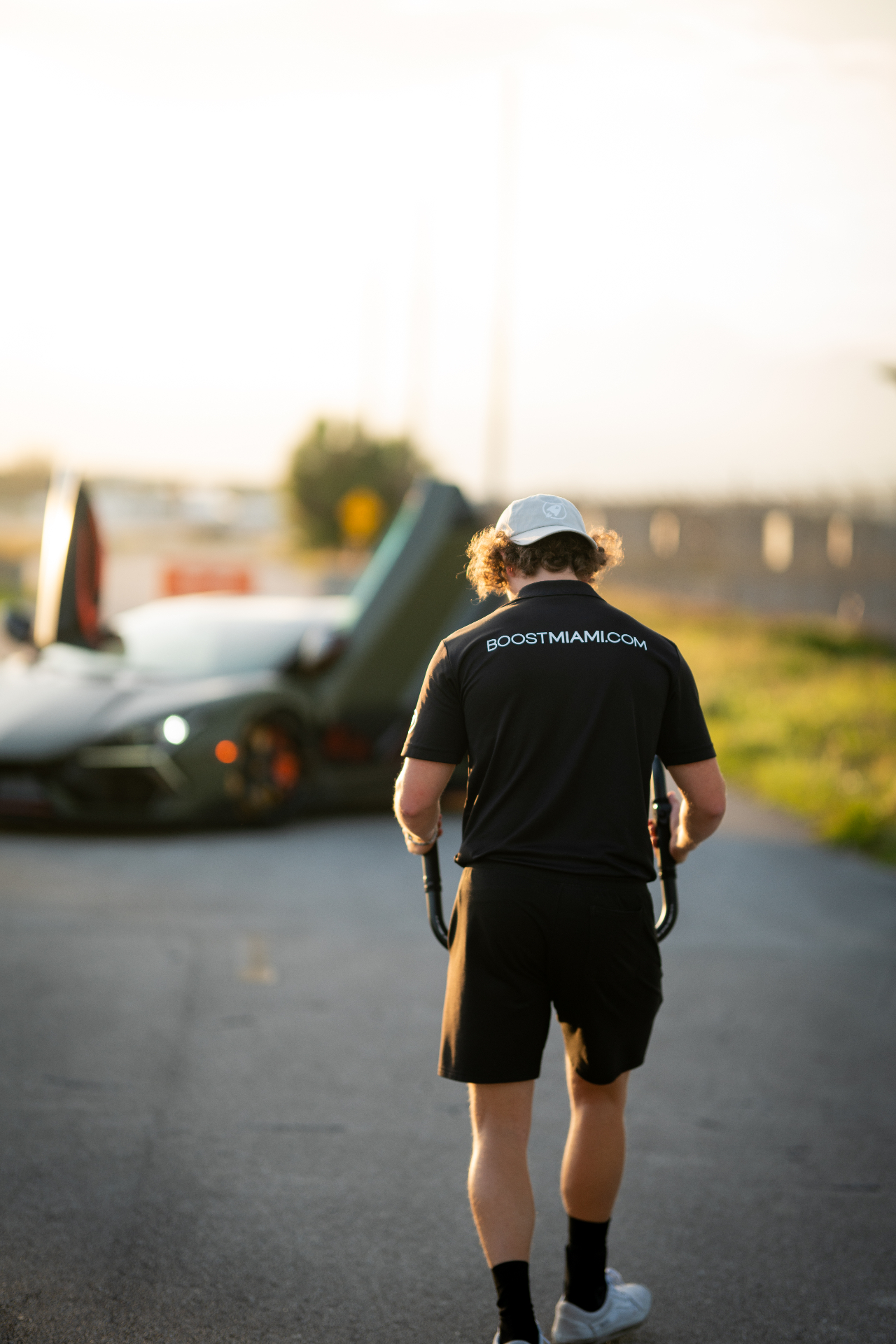 Boost team member walking toward a supercar at sunset